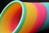 Close up of Opaque Rainbow Original HyperSpring, coils tilted at an angle on a black background
