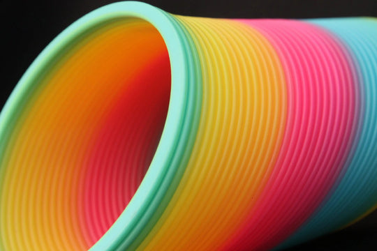Close up of Opaque Rainbow Original HyperSpring, coils tilted at an angle on a black background