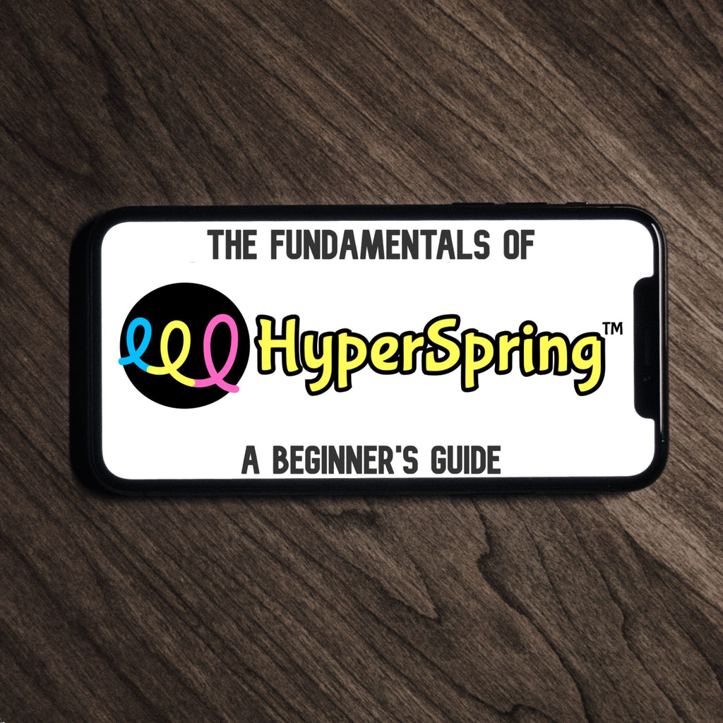 Smart phone lying on table, showing "The Fundamentals of HyperSpring: A Beginner's Guide" logo on the screen
